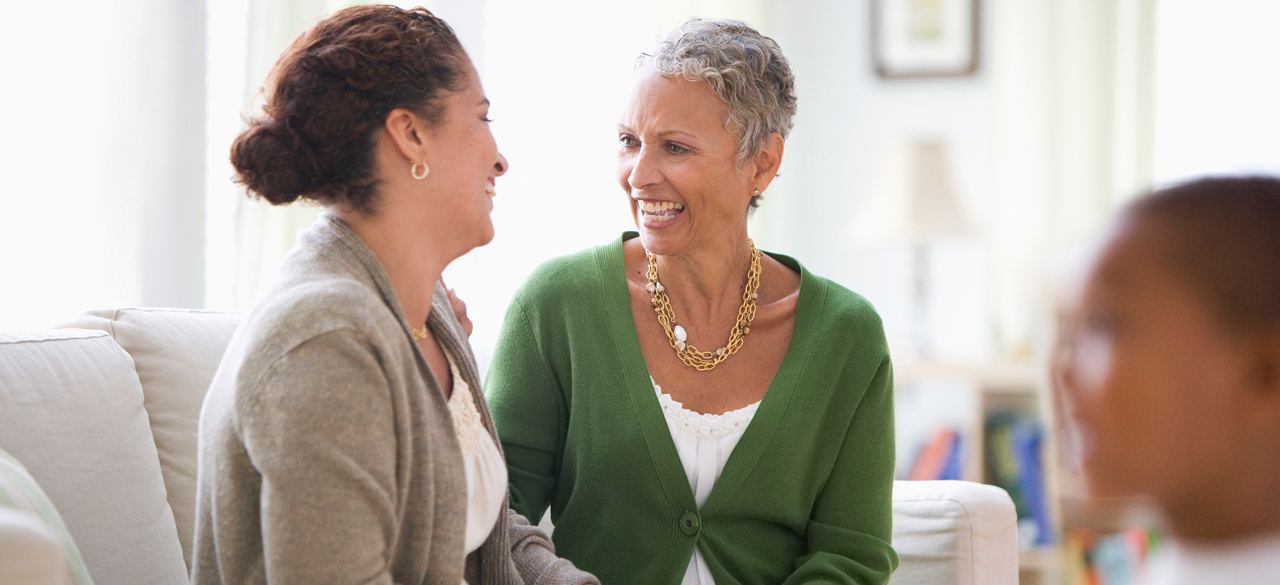 Two middle aged woman sitting on couch talking