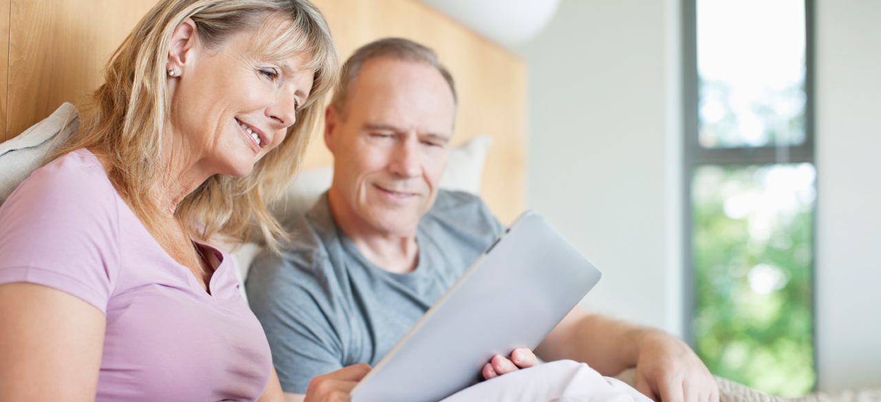 Couple sitting at table looking at laptop screen together