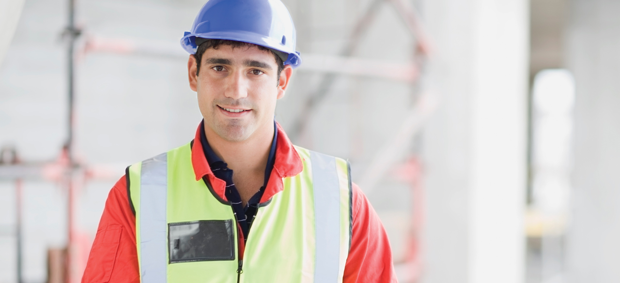 Man wearing a hard hat smiling at camera with blurred background
