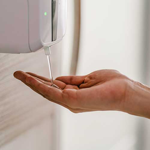 Machine distributrice de désinfectant pour les mains et main d’une personne