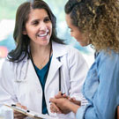Femme médecin qui parle à une patiente en souriant