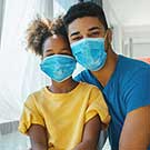 Père et sa fille portant des masques et posant pour une photo