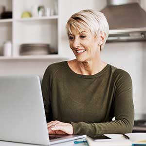 Middle aged woman sitting at table with laptop